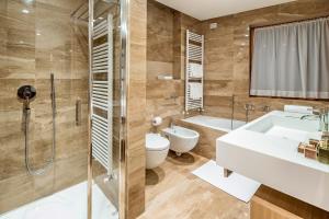a bathroom with a tub, toilet and sink at Hotel Lajadira & Spa in Cortina dʼAmpezzo