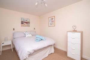 a bedroom with a white bed and a dresser at Bright Contemporary Merchant City Flat in Central Location in Glasgow