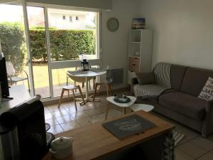 a living room with a couch and a table at Appart Les Goélands piscine et jardin in Andernos-les-Bains