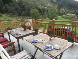 2 mesas de madera y sillas en un balcón con vistas en Landhaus Rieding, en Mühlbach am Hochkönig