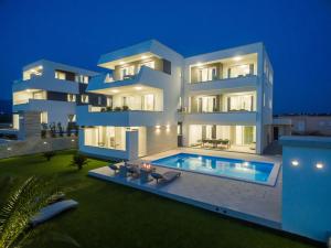 a large white building with a swimming pool at night at Apartments & Rooms Pool Villas Maris in Novalja