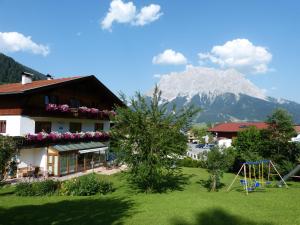 a building and a playground with a mountain in the background at Appartements Alpenland in Lermoos