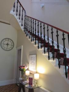 a staircase in a house with a clock on the wall at Seton Guest House in Glasgow