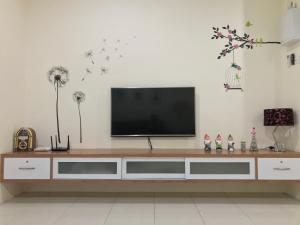 a living room with a television on a white wall at Kt Cozy Lodge in Kuala Terengganu