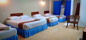 a hotel room with four beds and a chair at Hotel K T Mutiara in Kuala Terengganu