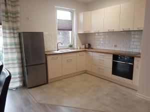 a kitchen with white cabinets and a sink and a refrigerator at Narutowicza Modern Apartment in Słupsk