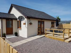 Casa blanca pequeña con porche y valla en Bonnie View Fort William Cottage en Fort William