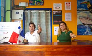 un hombre y una mujer de pie en un escritorio con el pulgar en alto en Hostel Mamallena, en Panamá