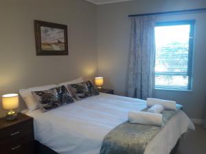 Schlafzimmer mit einem großen weißen Bett und einem Fenster in der Unterkunft Field's Rest: The Apartment in Port Elizabeth