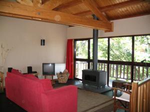 a living room with two red chairs and a television at Casa do Castanheiro in Outeiro