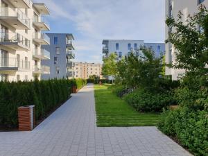 a walkway between two apartment buildings with grass at Apartament North Coast - nad morzem in Gdańsk
