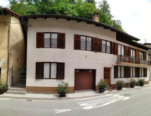 a large white house with brown shutters on a street at Hiša Kala in Kobarid