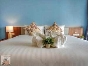 Louis' Runway View Hotel - SHA Extra Plus في شاطئ ناي يانغ: سرير عليه مناشف حيوانات عليه نبات