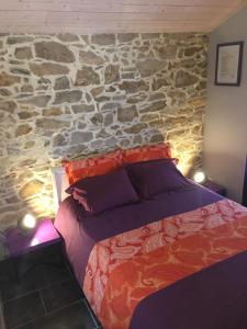 sypialnia z kamienną ścianą i łóżkiem w obiekcie La Forestière Pigeonnier w mieście Monclar-de-Quercy