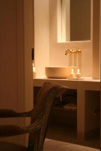 ein Badezimmer mit einem Waschbecken, einem Spiegel und einem Stuhl in der Unterkunft Castello Camemi in Vizzini