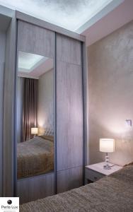 Perla Lux Apartments في أراندجيلوفاك: مرآة كبيرة في غرفة النوم مع سرير