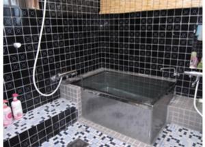 a bath tub in a tiled bathroom with a shower at Yakushima Park Guesthouse in Yakushima