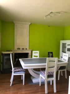 une salle à manger avec des murs verts et une table et des chaises blanches dans l'établissement Chez Lysette, à Mesnac