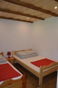 a bedroom with two beds and a white wall at Domek nad Krutynią in Piecki