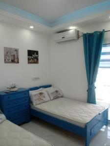 - une chambre avec un lit bleu et une fenêtre dans l'établissement B&A Paralia, à Paralia Katerinis
