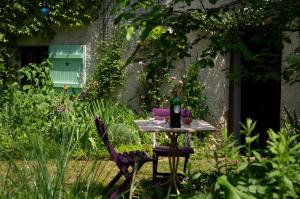 a table in a garden with a bottle of wine on it at Gîte Chez Dimanche in Essert