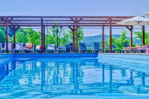 a swimming pool with chairs and an umbrella at Belle Royalle in Lisarnya