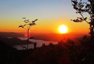 a sunset on a mountain with the sun in the background at Apartma Alpski vrt in Vojsko