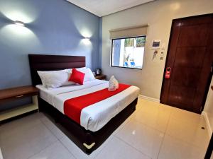 a bedroom with a large bed with a red blanket at Charms Hotel in Coron