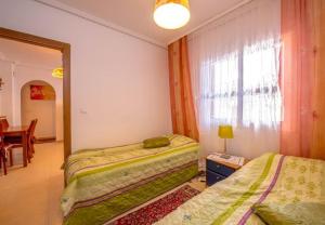 sypialnia z dwoma łóżkami, stołem i oknem w obiekcie APARTAMENTO "CARMEN" Zeniamar w mieście Orihuela