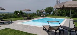 a swimming pool with chairs and an umbrella at Poggio di Pastrengo in Pastrengo