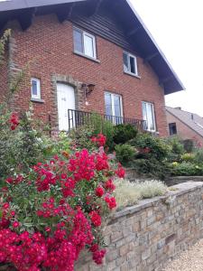 a brick house with red flowers in front of it at Bed vue sur vallée de la Meuse Namur in Bouge