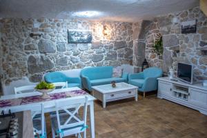 una sala de estar con muebles azules y una pared de piedra. en Traditional Stone House St.Anton, en Malinska