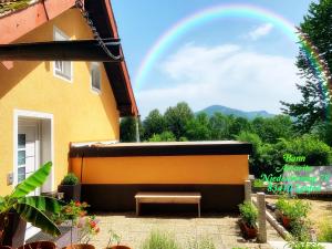 una panchina seduta fuori da un edificio con un arcobaleno nel cielo di Ban Amarita a Laufen