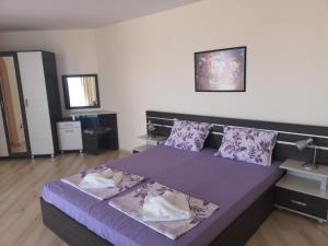 - une chambre avec un lit doté de draps et d'oreillers violets dans l'établissement Rose Garden Omax Apartments, à Sunny Beach
