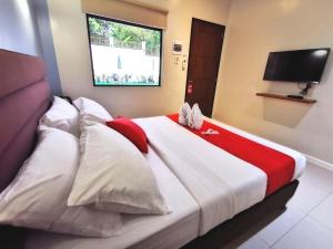 a bedroom with a large bed with red and white pillows at Charms Hotel in Coron