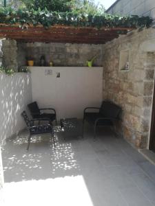 a patio with three chairs and a table and a wall at Apartman Ivana in Splitska