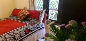ein Bett mit Kissen neben einem Fenster in der Unterkunft Evergreen in Kandy