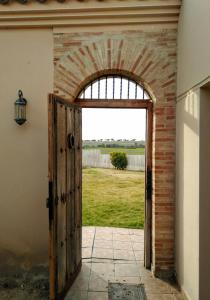 une porte ouverte menant à un mur de briques avec une arche dans l'établissement Casas Olmo y Fresno jardín y piscina a 17 kilómetros de Salamanca, à Salamanque