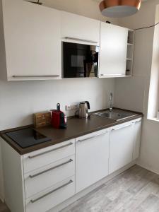 a kitchen with white cabinets and a black counter top at Apartmán Pisek centrum in Písek