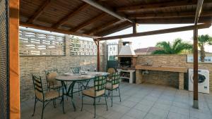 eine Terrasse mit Tisch und Stühlen und eine Außenküche in der Unterkunft Villa, Private heated pool and jacuzzi . in Maspalomas