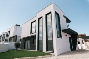 uma casa branca com grandes janelas de vidro em Obidos House with private pool em Bairro
