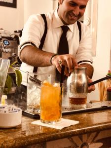 a man in a tie stirring a drink on a counter at camere pula in Pula