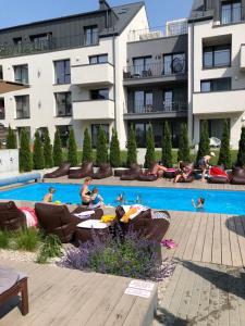 a group of people sitting around a swimming pool at Malūnų vilos in Palanga