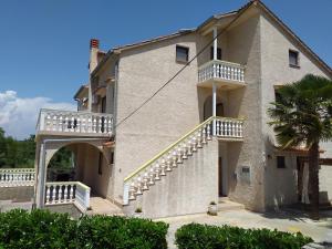 a large building with stairs and a palm tree at Apartments I-P in Malinska