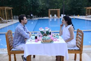 a man and woman sitting at a table in front of a pool at Suna Village Hotel & Bungalow Fethiye in Fethiye