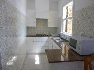 a kitchen with white cabinets and a microwave at Apartamentos Playa Calan Blanes in Cala en Blanes