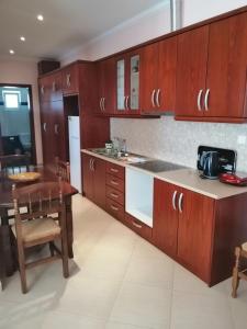 a kitchen with wooden cabinets and a table and a dining room at Helen's House in Ksamil