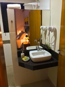 a bathroom with a sink and a mirror at Pousada Divina Minas in Três Corações