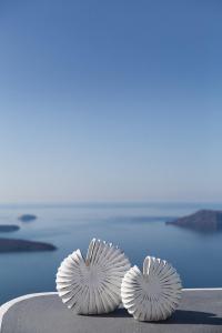 two white fans sitting on a ledge overlooking the ocean at Thea Apartments in Imerovigli