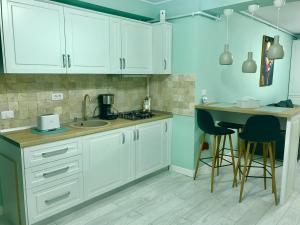 a kitchen with white cabinets and a table with stools at DarNiDa Luxury Apartment in Mamaia Sat/Năvodari